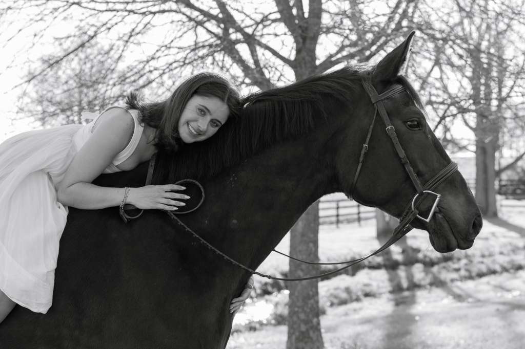 Chloe leaning on her horse, black and white