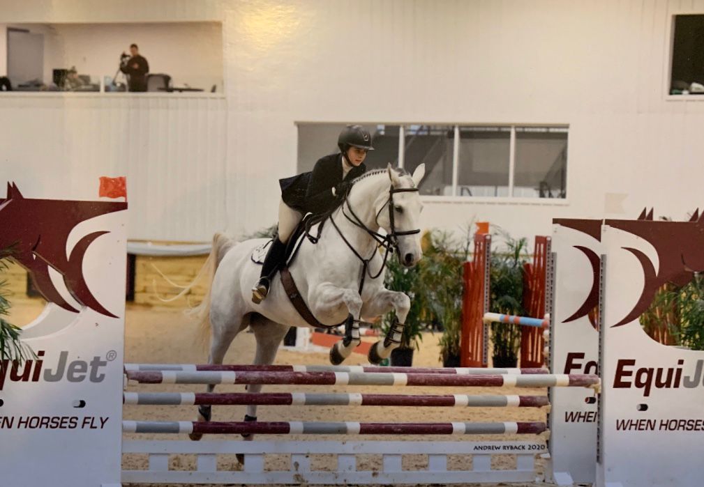 Chloe jumping a white horse
